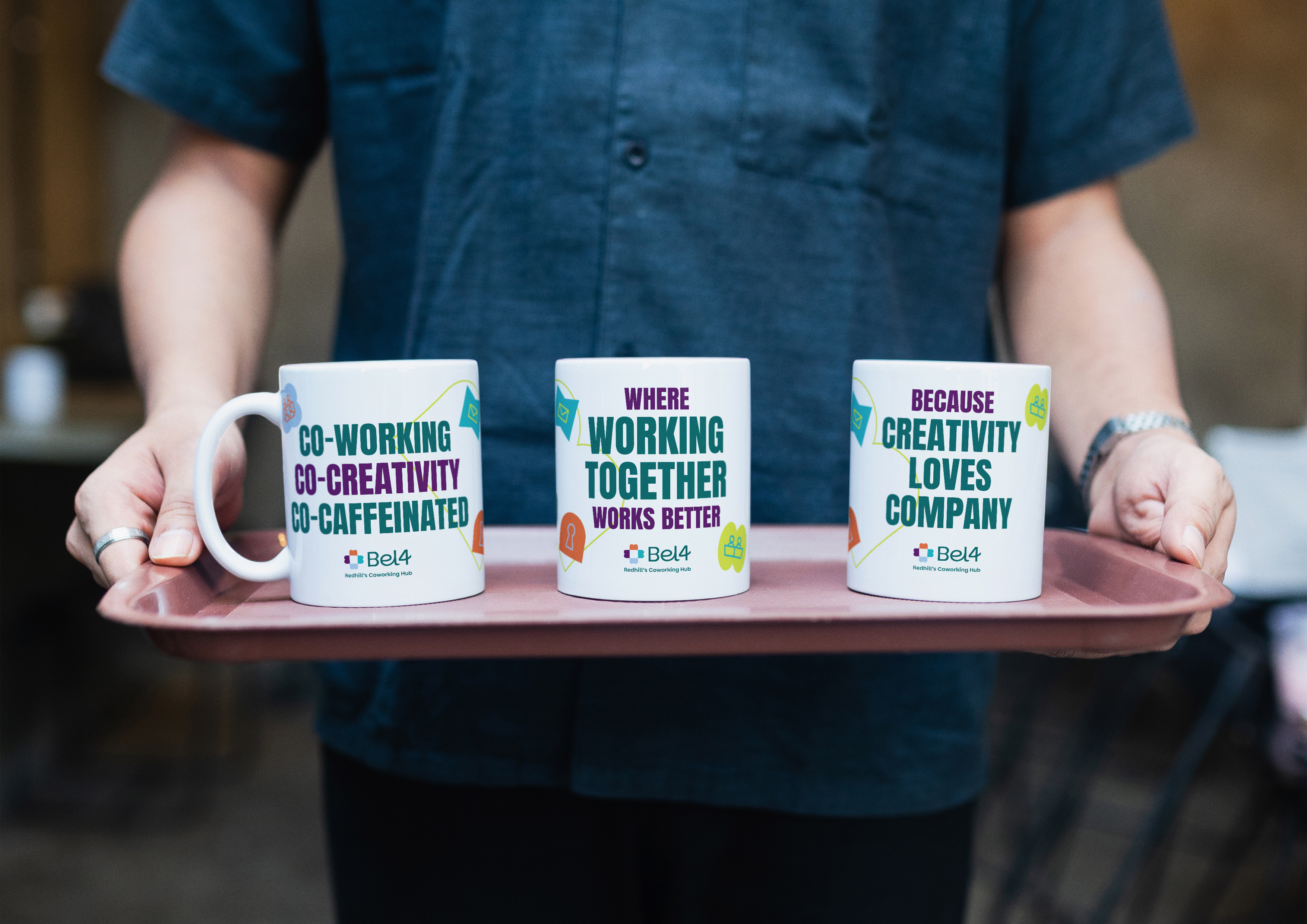 An image showing a man carrying a tray with three white mugs with Bel4 branding and slogans on them